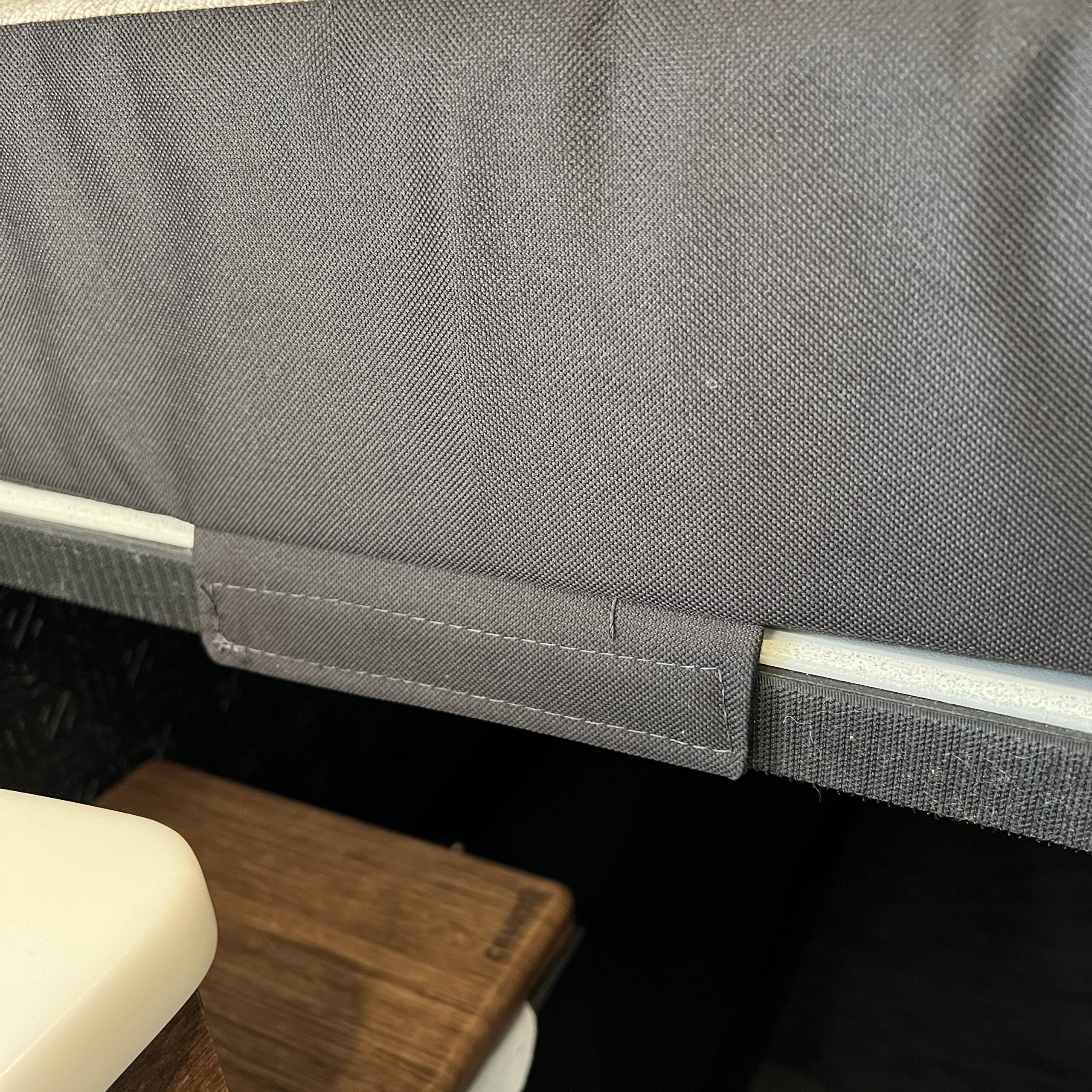 Close-up of Luxe5 Cooling Memory Foam mattress edge in a van interior with fabric cover and wood platform.