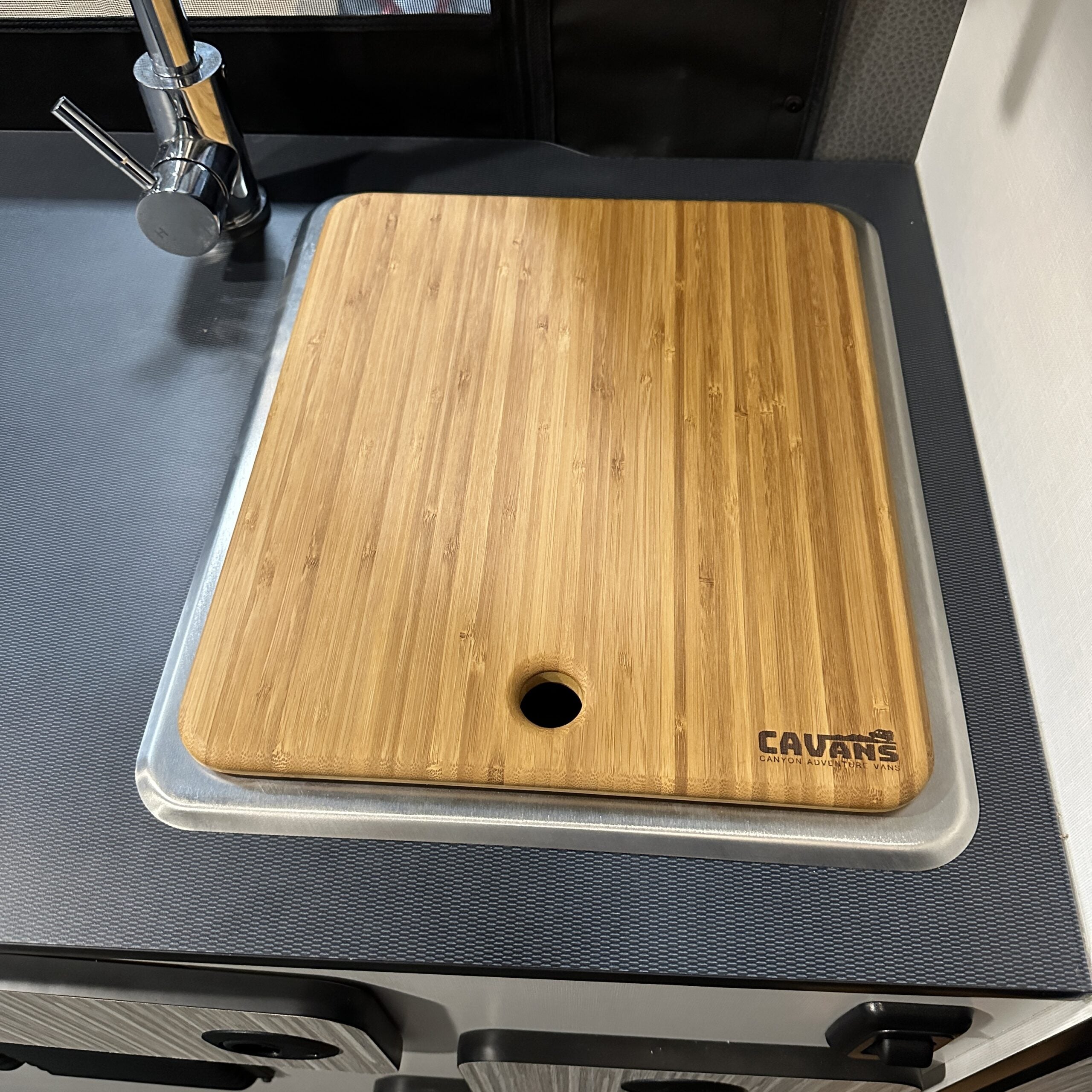 CAVARTS bamboo sink cover on a van kitchen counter with built-in faucet.