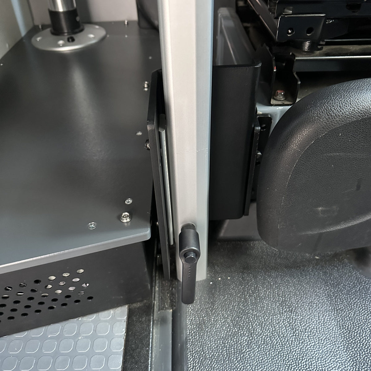 table mount Long Leg mounted between van seat and metal cabinet in a compact van interior.