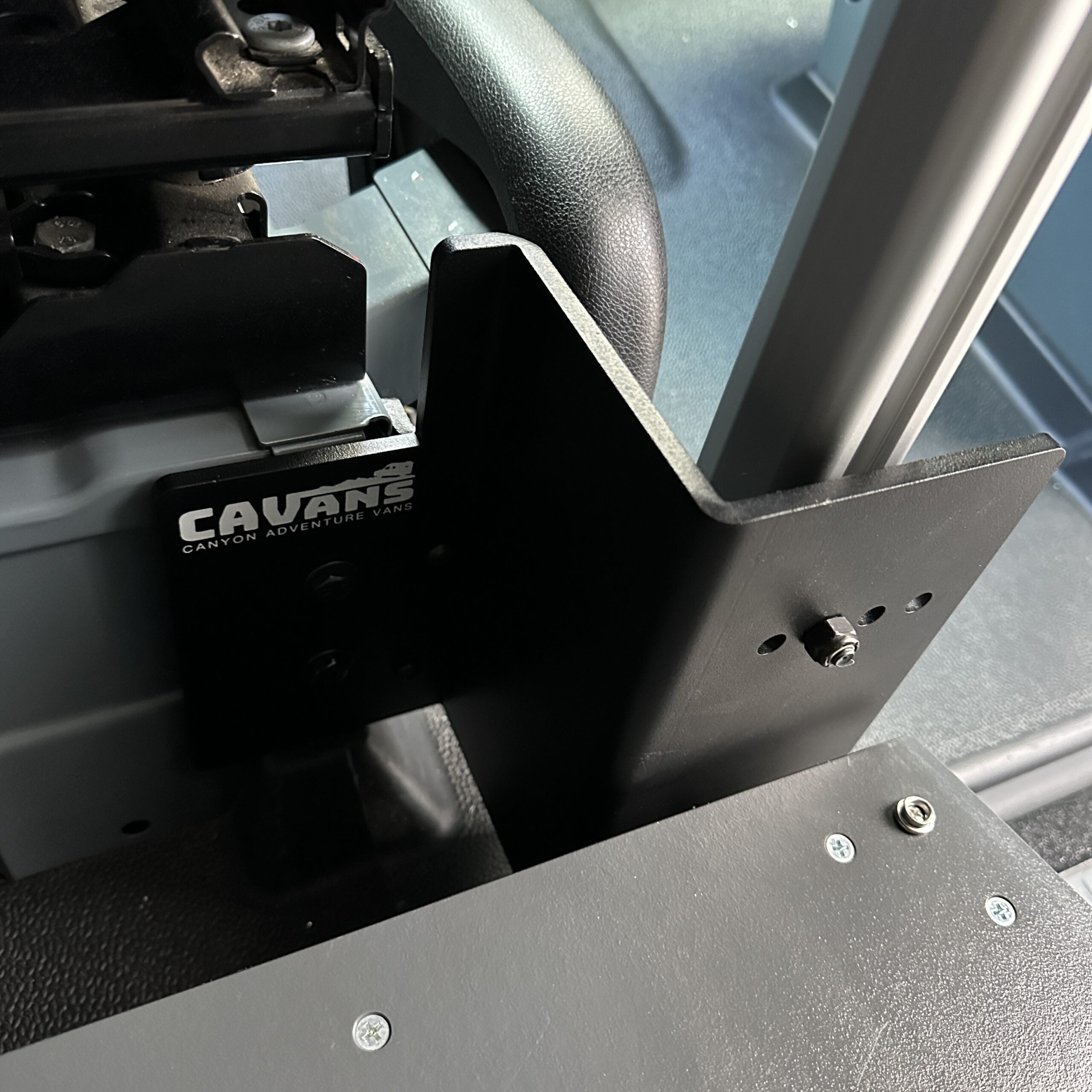 CAVAN console table bracket installed in a van interior near driver seat frame