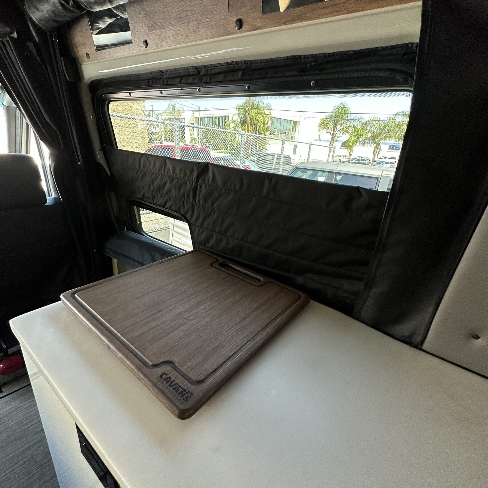 Clima-Shade window cover installed in a Storyteller van with a dark wood cutting board on counter