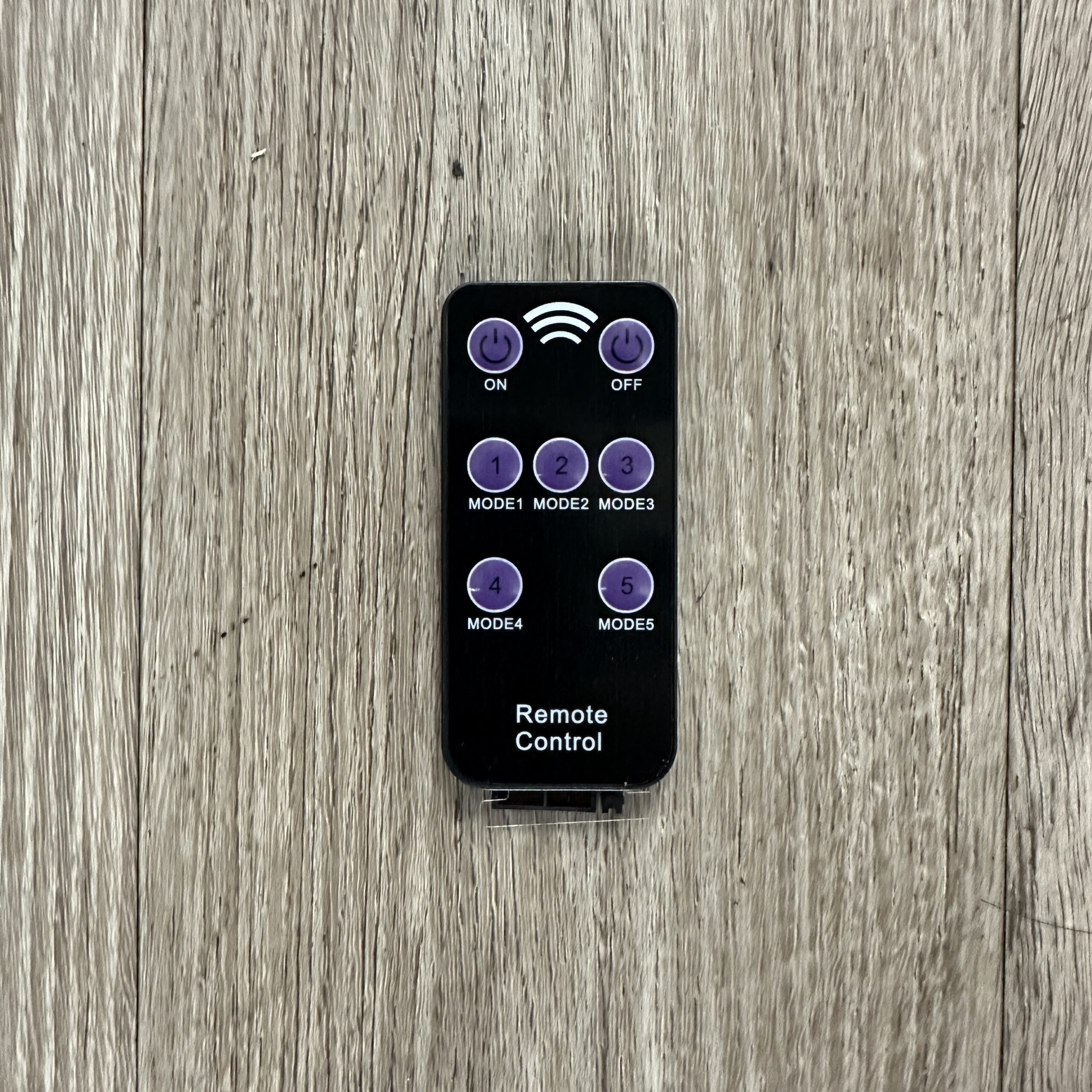 Remote control for Canyon Motion Sensor Solar Light shown on wood surface