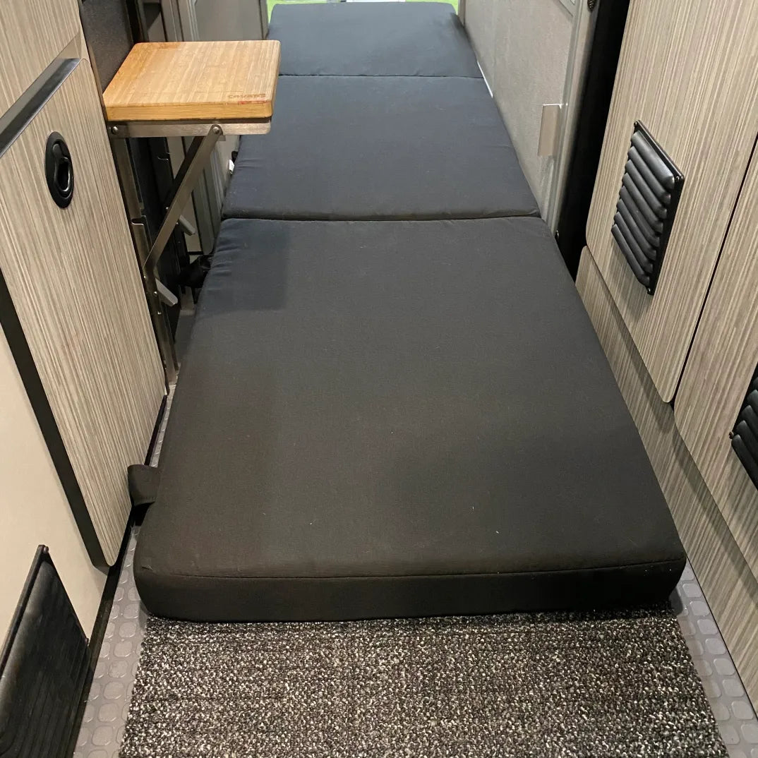Revel floor mattress laid out flat in van aisle with fold-out table nearby