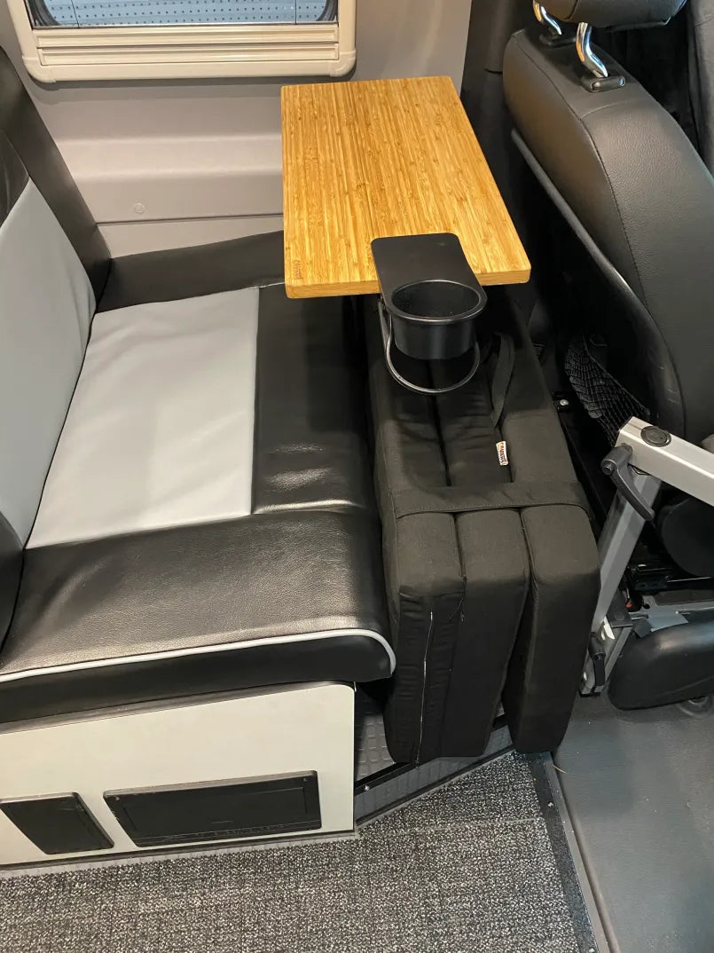 Revel floor mattress folded beside van bench seat with wooden table and cup holder attached