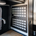 Revel Kitchen MOLLE panel mounted on van wall beside faucet and wooden countertop