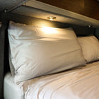 Revel Dream Collection adjustable pillow on a made bed inside a van with overhead lighting