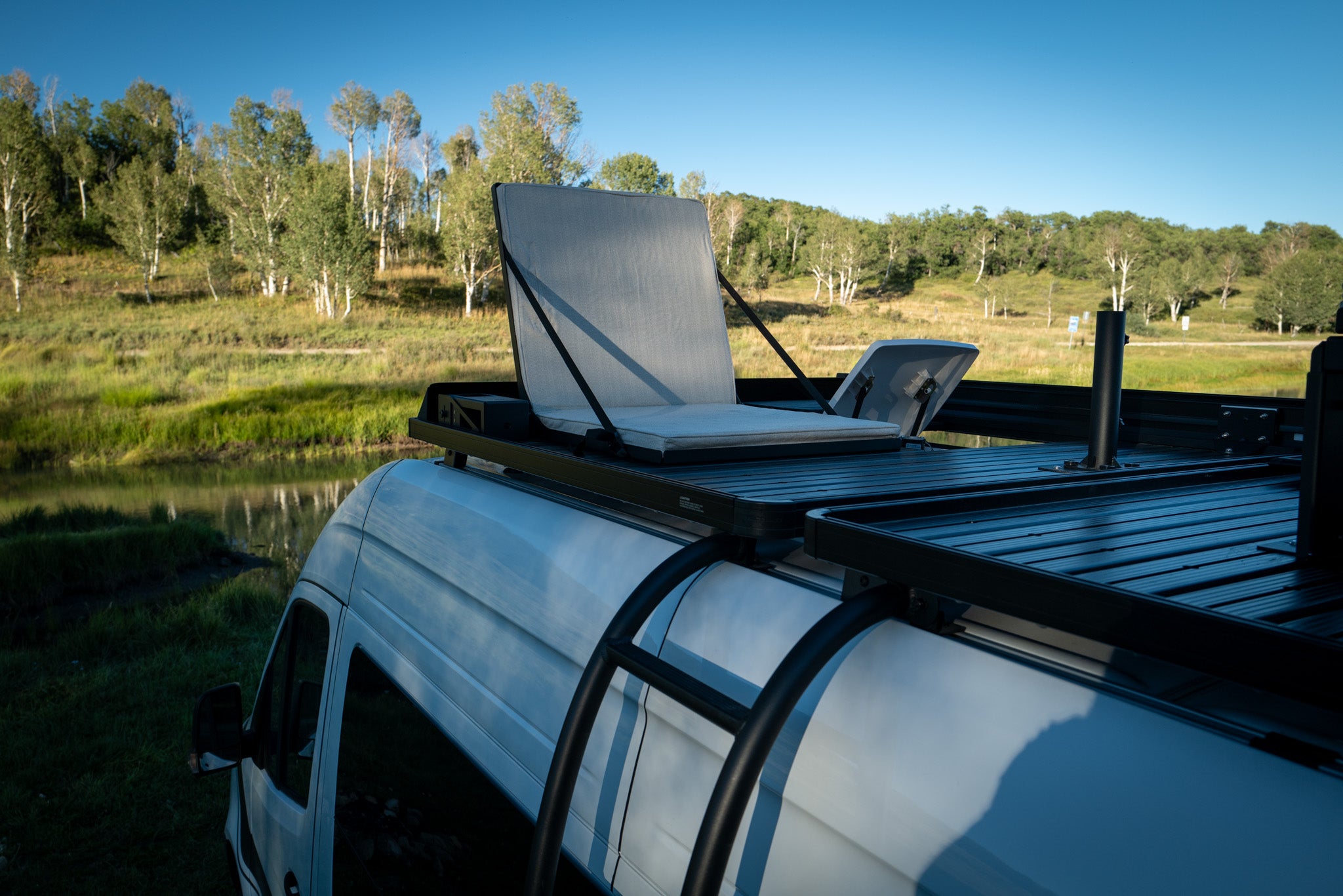 Van roof rack seating with cushioned chairs and umbrella