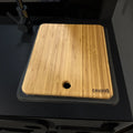 Bamboo sink cover with drain hole on black van countertop, engraved with CAVANS logo.