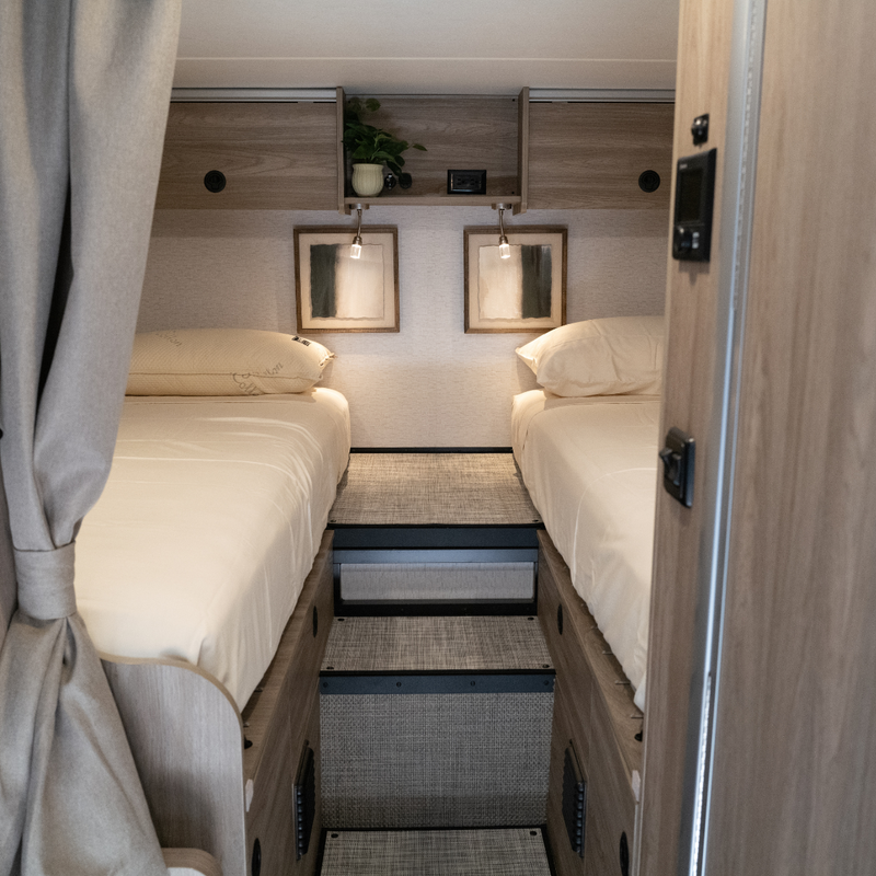 Twin beds with neutral bedding and wall art inside a Winnebago Ekko van featuring the Ultra Luxe Mattress.
