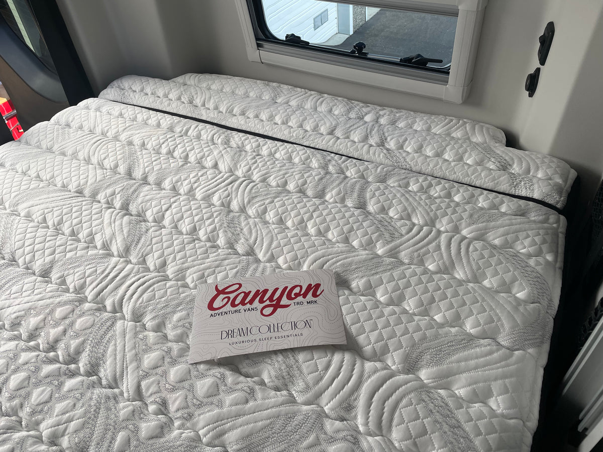 Revel Ultra Luxe mattress in a van with stitched white quilting and window view.