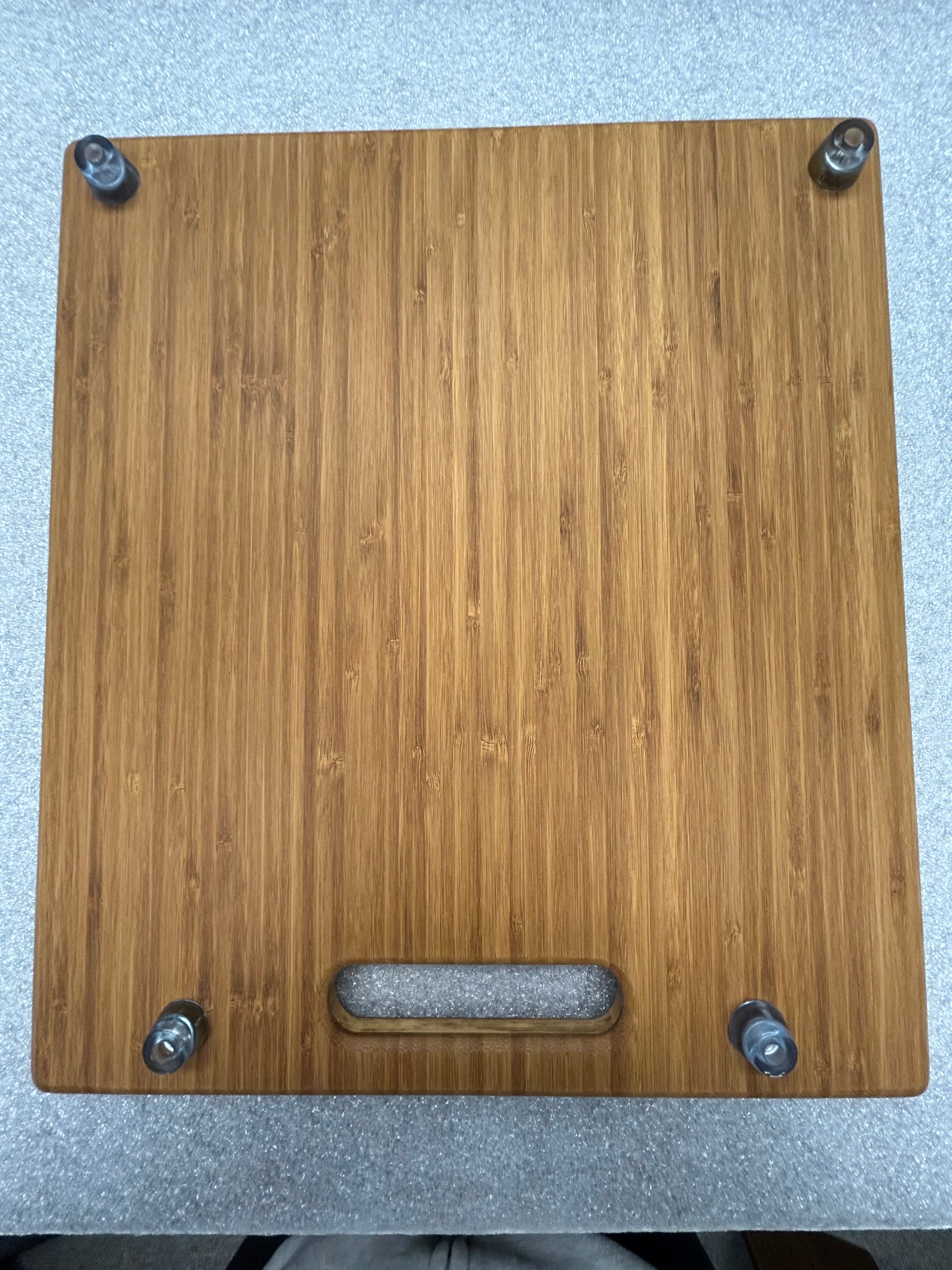 Revel bamboo cutting board with handle and mounted hardware, set on a countertop