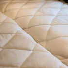 Quilted beige mattress topper from the Dream Bundle inside a van.