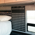 Storyteller Shower MOLLE panel mounted on van wall beside bed and window