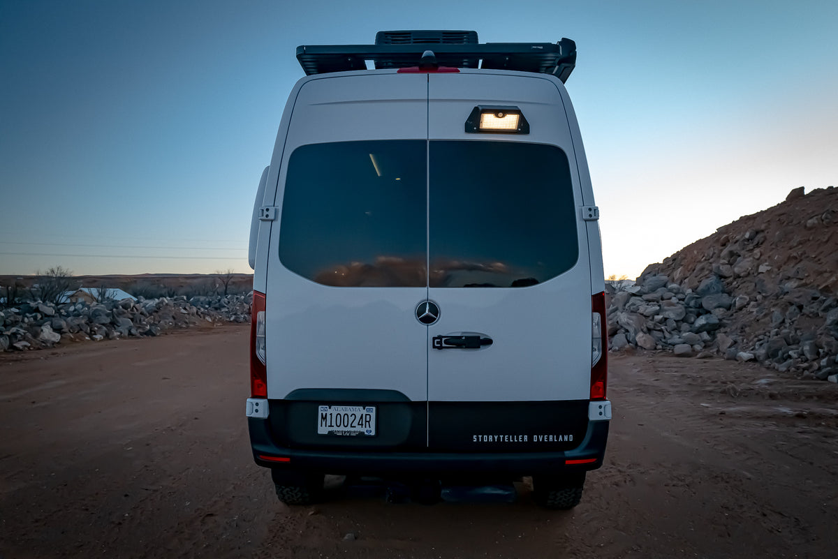 Back view of a white Mercedes-Benz van in a desert landscape showing illuminated magnetic solar motion sensor light 