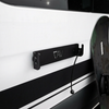 CAV magnetic ski and snowboard holder mounted on van exterior with a snowboard leaning nearby