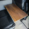 Large Universal Table Top in wood finish installed between van seats with black tufted upholstery.