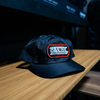 Black Chatsworth Hat with Canyon Adventure Vans patch on wooden surface