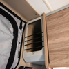 Ekko Cab Cubby by CAV mounted on interior van wall next to wood cabinet and insulated shade.