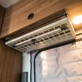 Ekko under cabinet shelf on driver side of van interior with wood paneling and overhead lighting