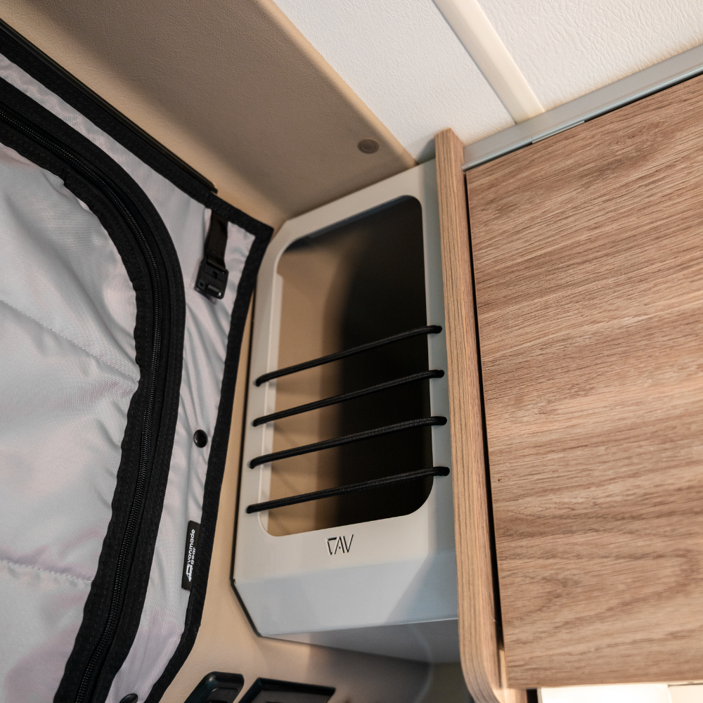 Ekko Cab Cubby by CAV mounted on interior van wall next to wood cabinet and insulated shade.