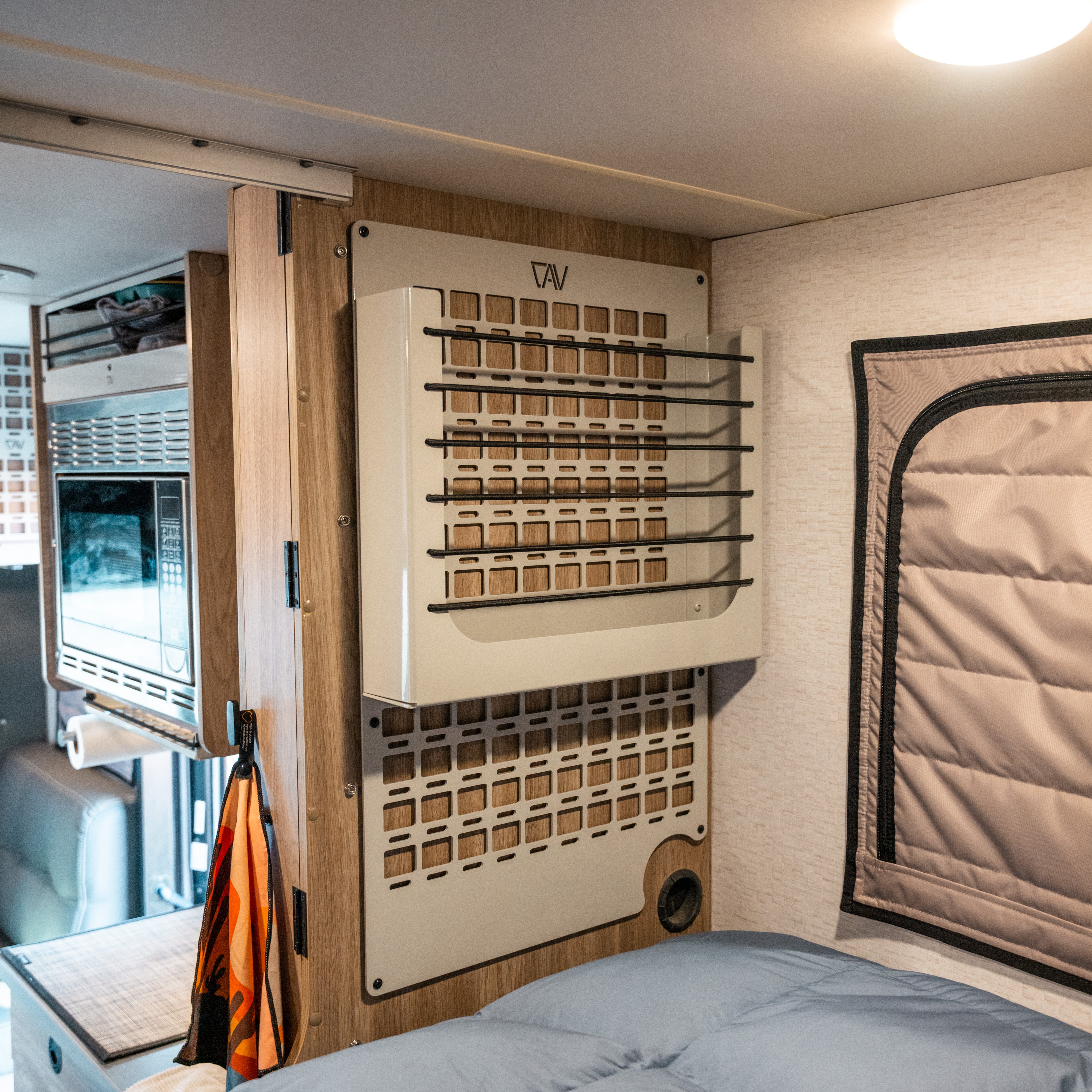 Ekko MOLLE Shelf System beige mounted on van interior wall near bed with ekko microwave showing in background