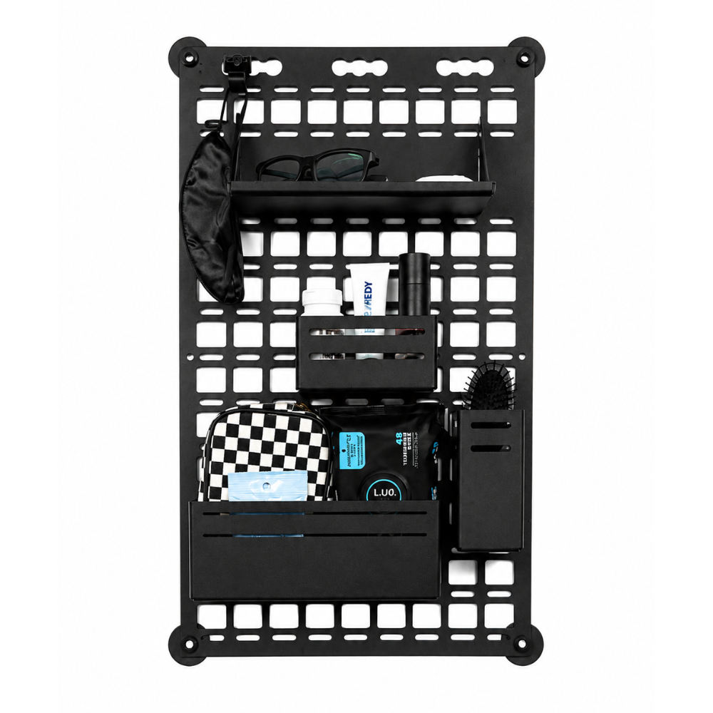 A black powdercoated aluminum wall-mounted molle panel with multiple shelves, hooks, and compartments, shown against a white background and filled with various toiletries and accessories for sprinter van storyteller overland mode
