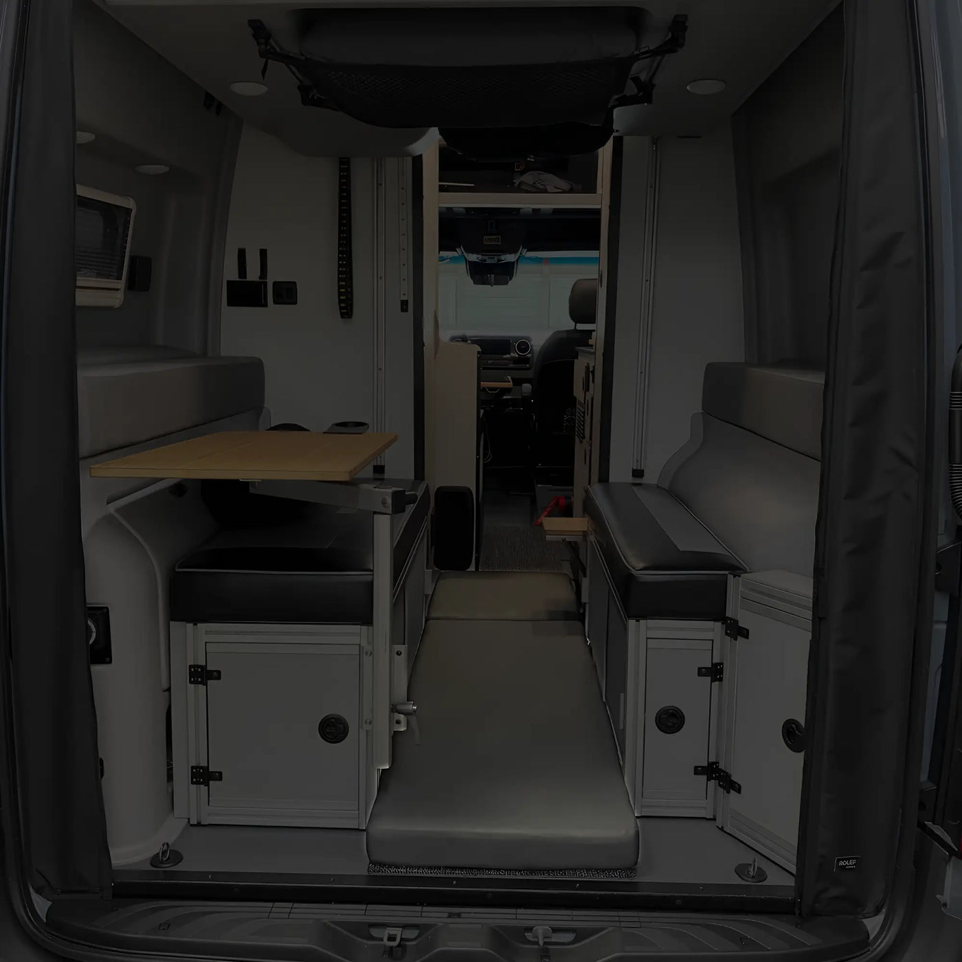 Revel floor mattress laid out between benches in the rear of a van interior setup for camping.