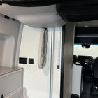 Revel bed harness cover secured to van wall near rear sleeping area and storage cabinet.