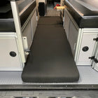 Revel floor mattress laid out between two benches in a van interior.